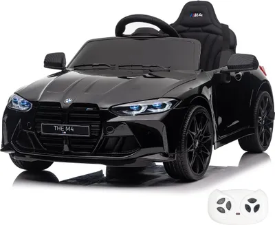 A black electric toy car, resembling a BMW M4 Competition, is shown from a front-side angle against a white background. A white remote control is visible in the bottom right corner.