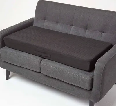 A dark gray seat cushion is placed on a dark gray sofa.