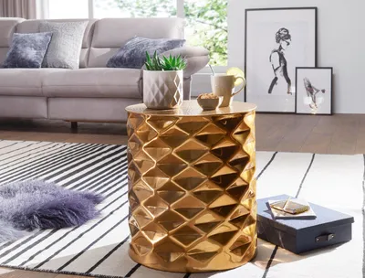 A living room scene with a sofa, rug, and a gold accent table.