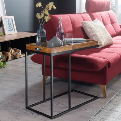A side table with decorative items on it is placed next to a red sofa in a living room.