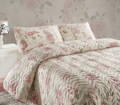 A close-up view of a king-size bed with a floral-patterned quilt and pillows.