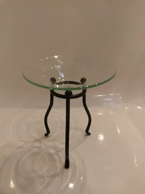 Duftlampe mit runden Glasteller auf einem schwarzen Metallständer mit drei Beinen.
