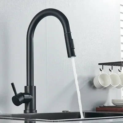 A black kitchen faucet with a pull-down sprayer is shown in use, with water flowing into a sink. Cups are hanging on a rack in the background.