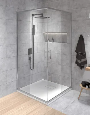 A modern bathroom with a glass shower enclosure, tiled walls, and wooden flooring.