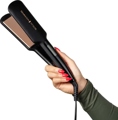 A hand with red nail polish holds a black hair straightener with gold plates against a white background.