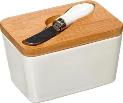A white ceramic butter dish with a bamboo lid and a butter knife resting in a cutout on the lid.