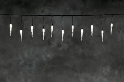 A string of icicle-shaped LED lights hangs against a dark, textured background.