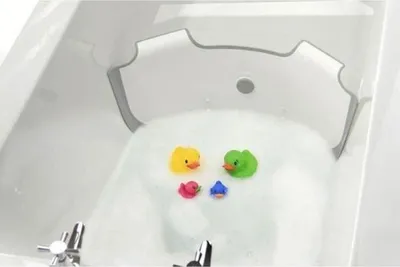 A baby bathtub insert with rubber ducks floating in the water.