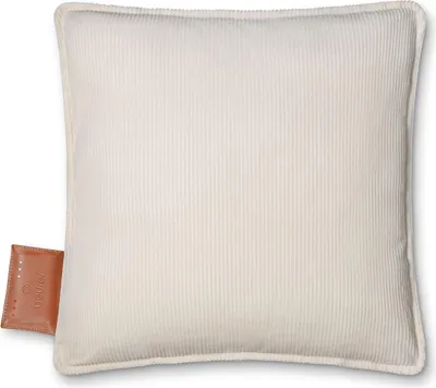 A close-up studio shot of a cream-colored, corduroy heating pad with a small brown leather tag attached to the bottom left corner.