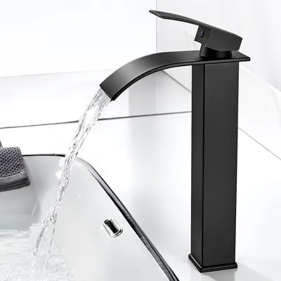 A black waterfall faucet in a modern bathroom, with water flowing into a sink.