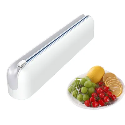 A white plastic wrap dispenser is shown next to a plate of fruit covered in plastic wrap.