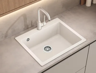 A white kitchen sink with a white faucet is shown on a light gray countertop.