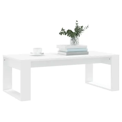 A white coffee table with a stack of books and a vase of greenery on top, set against a white background.