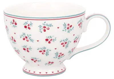A white teacup with a floral pattern of red berries and green leaves, and blue and red trim around the rim and base.