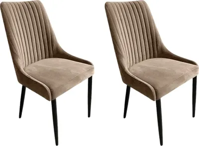 Two beige velvet dining chairs with black legs are shown against a white background.