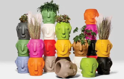 A collection of colorful, head-shaped planters stacked in a pyramid formation.