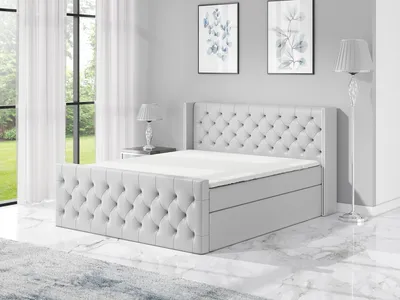 A light gray upholstered boxspring bed with a tufted headboard and two storage drawers is shown in a bedroom setting.