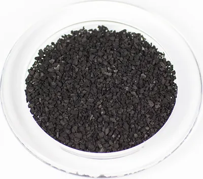 A close-up, top-down view of black charcoal granules in a clear glass dish.