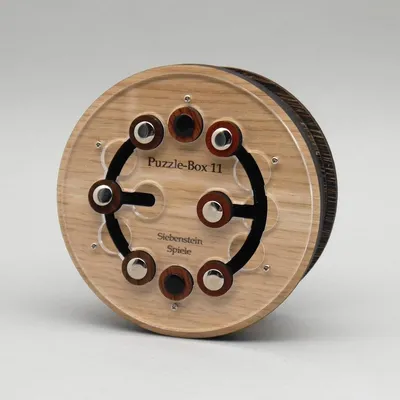 Runde Trickkiste aus hellem Holz mit kreisförmig angeordneten Knöpfen und sichtbarem Denkspiel-Mechanismus.
