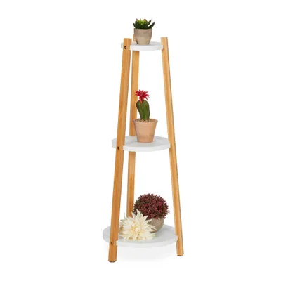 A three-tiered plant stand made of wood and white shelves, decorated with three potted plants.