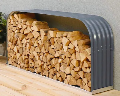 A firewood rack filled with logs, placed on a wooden deck against a textured wall.