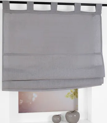 A grey Roman blind with fabric loops hangs in front of a window.