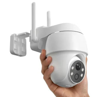 A hand holding a white security camera with two antennas.