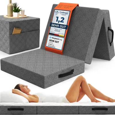 A folded mattress is shown with a woman lying on a bed in the foreground, and a side table with decorative items in the background. There is also a certification label attached to the mattress.