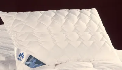A white quilted pillow with a label attached.