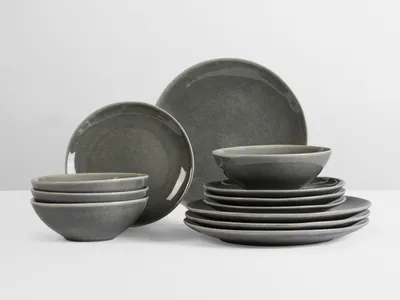 A set of grey ceramic plates and bowls are arranged on a white background.