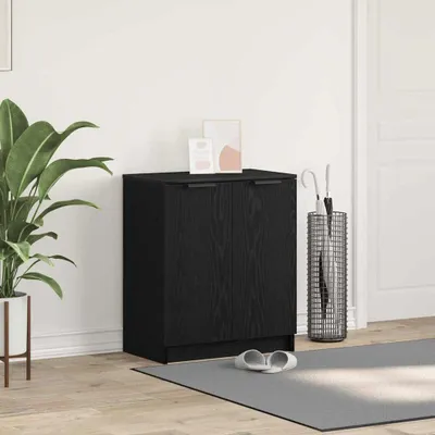 A black wooden cabinet with two doors, placed in a room with a plant, an umbrella stand, and a mat with slippers.