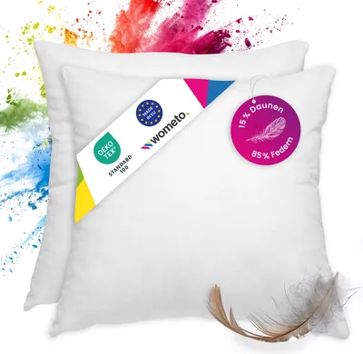 Two white pillows are shown with colorful powder splashes in the background. Product tags are attached to the pillows.