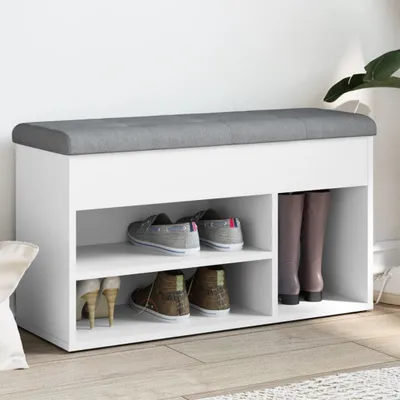 A white shoe bench with a gray upholstered top, displaying various shoes on its shelves.