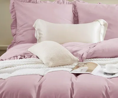 A close-up view of a neatly made bed with pink bedding and pillows.