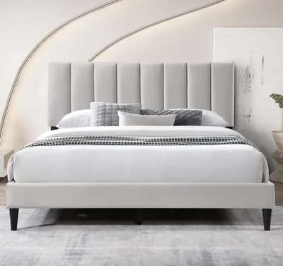 A bed with a padded headboard and bedding in a room.