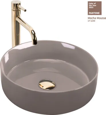 A close-up studio shot of a round beige vessel sink with a gold drain and a gold faucet.