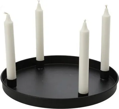 Four white candles are placed in a black circular tray.