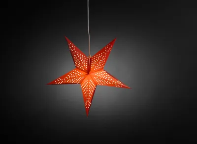 A red paper star lantern with white perforations hangs against a dark gray background.