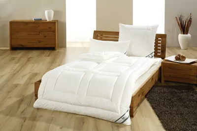 A neatly made bed with white bedding in a room with wooden furniture.