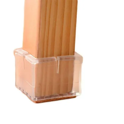 A close-up of a clear plastic chair leg cap on a wooden table leg.