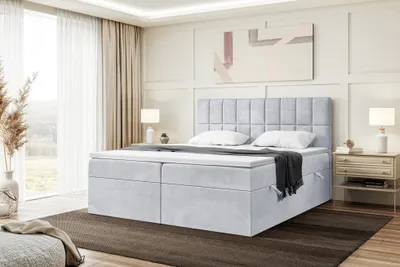 A bedroom scene featuring a large boxspring bed with a headboard, two bedside tables, and a large window with curtains.