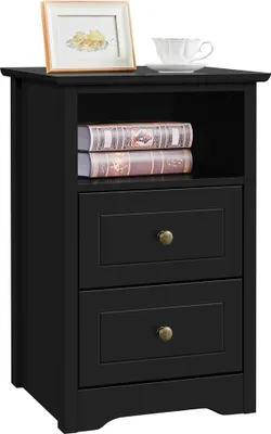 A black nightstand with two drawers and an open shelf, decorated with a framed picture and a teacup on top.
