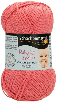 A ball of coral-colored yarn with a label showing brand and product information, including a picture of a baby.