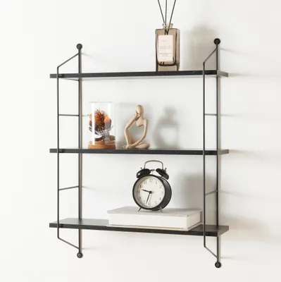 A three-tiered black wall shelf with decorative items.