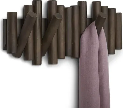 A wall-mounted coat rack with several hooks, one of which is holding a folded scarf.
