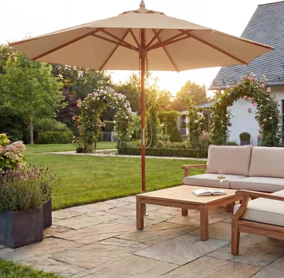 A garden patio with outdoor furniture and a large umbrella, set during golden hour.