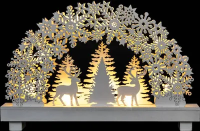 A decorative Christmas arch with snowflakes, trees, and reindeer, illuminated by warm lights.
