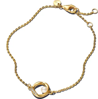 A close-up studio shot of a gold bracelet with a pearl and diamond accent.