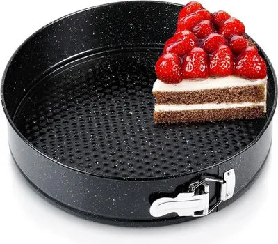 A slice of cake topped with strawberries sits inside a black springform pan.