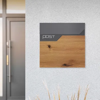 A modern mailbox with a wood-grain finish is mounted on a textured white wall next to a gray door.